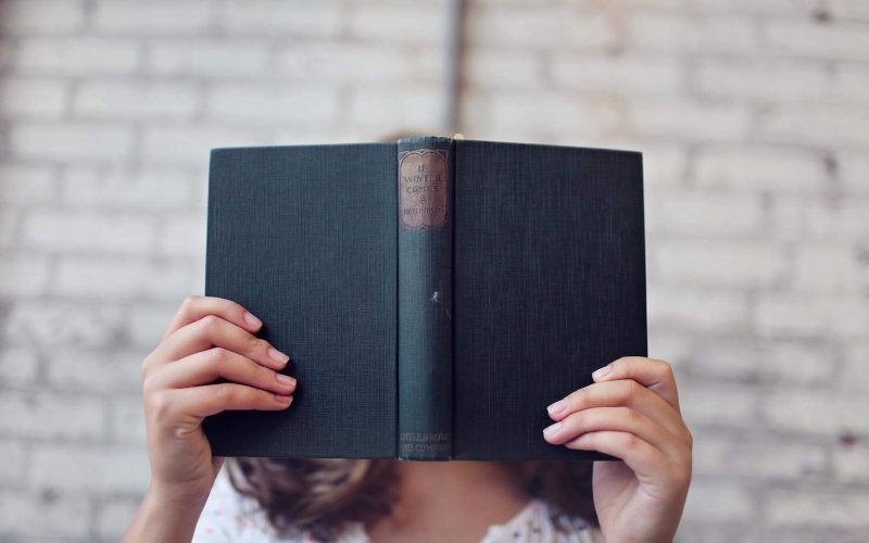 selective focus photography of woman holding book